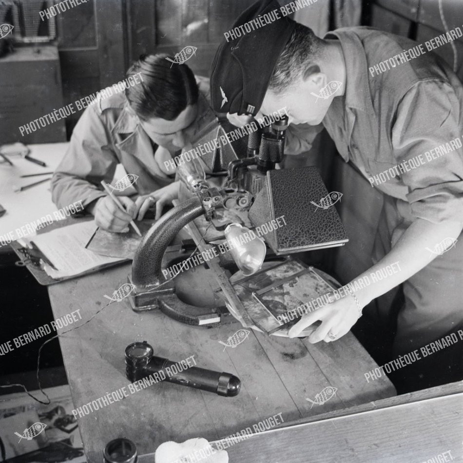 F677 À l'aide d'un stéréoscope un des officiers du service photo examine les résultats d'un bombardement. MARAUDERS B26 FRANÇAIS 1944